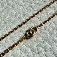 Gold chain with a clasp on a light gray textured background