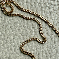Gold chain necklace on a textured light gray surface