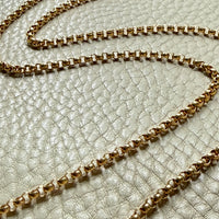 18k Gold antique rolo link necklace on a textured light gray surface