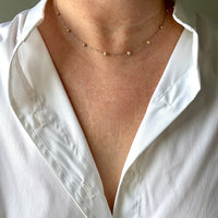 Person wearing a white shirt with a platinum and pearl station necklace