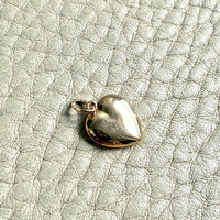 Gold heart-shaped pendant on a textured light gray background
