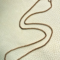 18k Gold antique rolo link necklace on a textured light gray surface