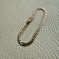 Gold chain bracelet on a textured gray surface
