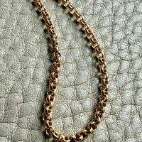 Gold chain necklace on a textured gray surface