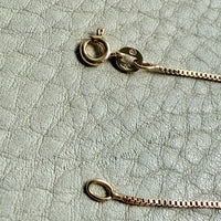 Gold necklace on a textured light gray surface