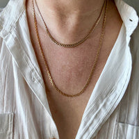 Person wearing a gold chain necklace with a white shirt.