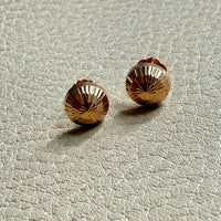 Pair of gold stud earrings on a light gray textured surface