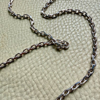 Silver chain necklace on a textured green surface