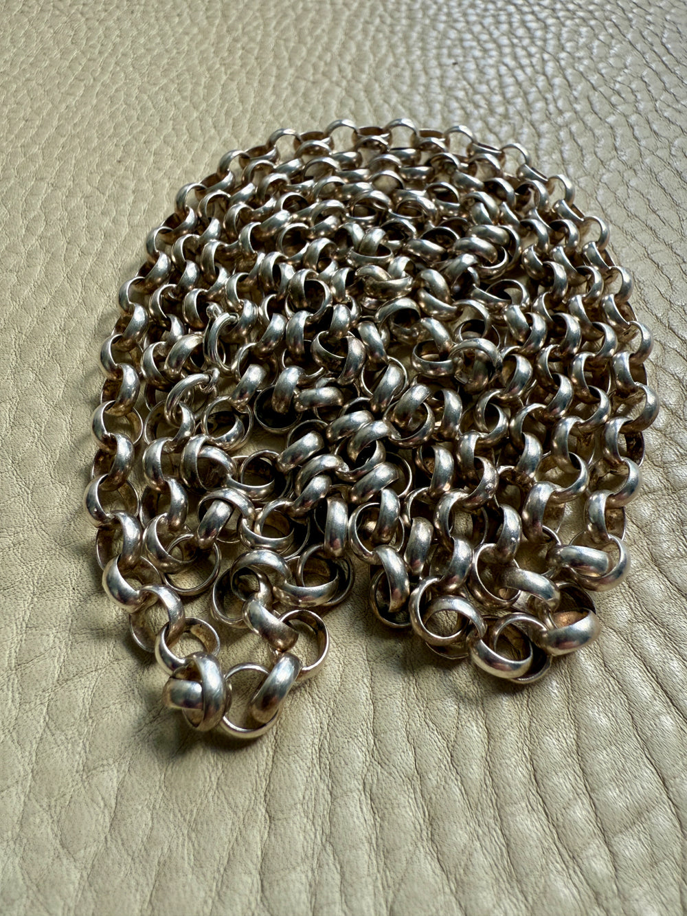Silver chain on a textured beige surface