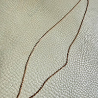 Gold chain on a textured beige surface