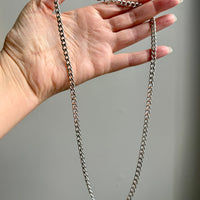 Hand holding a vintage 14k white gold chain chain against a gray background
