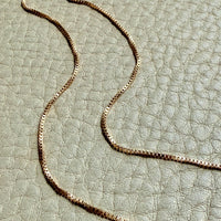 vintage 18k gold chain necklace on a textured light green surface