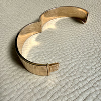 Gold bracelet on a textured beige surface