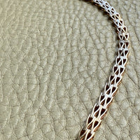 gold chain necklace on a textured beige surface