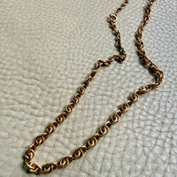 Gold chain necklace on a textured light gray surface