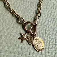 Gold Necklace with charms on a textured beige background