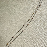 french antique platinum Necklace with pearl beads on a textured beige surface