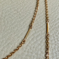 Gold chain necklace on a light gray textured background