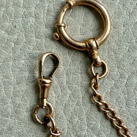 18k Gold antique watch chain necklace on a light gray textured surface
