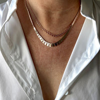 Necklace with square links on a person wearing a white shirt.