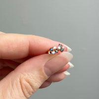 Hand holding a small earring with a gray background