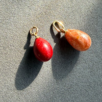 Two stone pendants on gold rings against a gray background