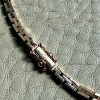 gold chain on a textured light gray surface