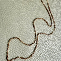 vintage 18k gold chain on a textured beige surface