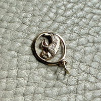 14k gold pendant with an aries ram design on a textured gray surface