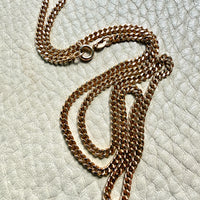 Gold chain necklace on a textured light gray surface