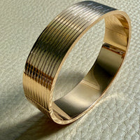 Gold bangle on a textured surface