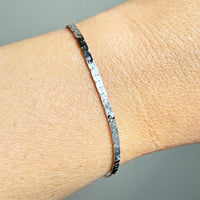white gold bracelet on a wrist against a gray background