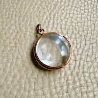 Clear pool of light pendant with rose gold setting on a textured beige surface