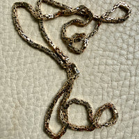 14k gold Gold byzantine chain necklace on a textured beige surface penelopepenelope.com fine jewelry