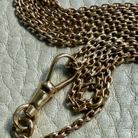 18k Gold chain necklace with dog clip on a textured surface