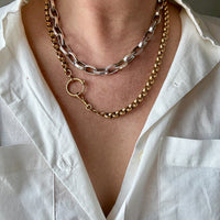 Necklace with gold and silver chains worn by a person in a white shirt.