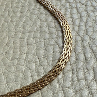 Close-up of a braided leather strap on a textured gray background. PenelopePenelope.com