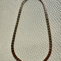 gold chain necklace on a textured light gray background