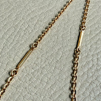 Gold chain necklace on a textured light gray background
