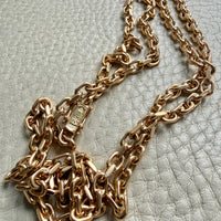 Gold chain necklace on a textured light gray surface