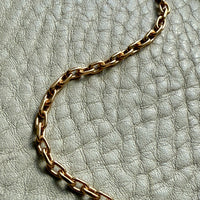 Gold chain necklace on a textured light gray surface