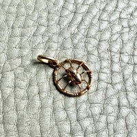 Small gold spider pendant on a textured gray surface