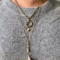 Gold necklace with pendant on a gray sweater