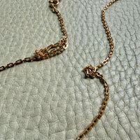 Gold necklace on a textured light green surface