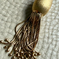 Gold tassel pendant on a textured surface