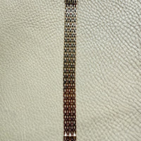 gold link bracelet on a textured light gray background