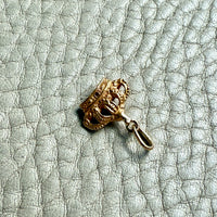 Gold crown-shaped pendant on a textured light blue background