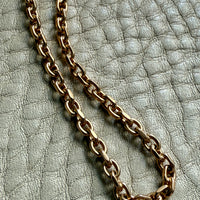 Gold chain necklace on a textured light gray surface