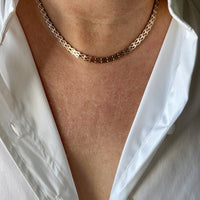 gold chain necklace worn by a person with a white shirt.