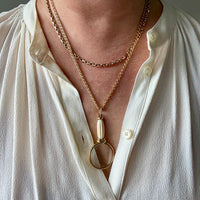 Person wearing a white shirt with layered necklaces